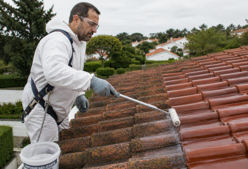 Trabalhador aplica uma solução impermeabilizante com um rolo