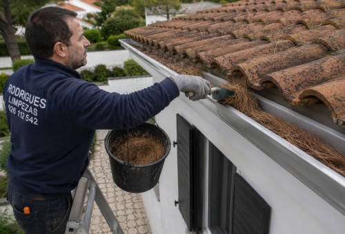 Trabalhador limpa os algerozes numa casa em Olhão
